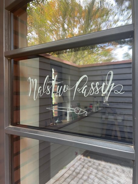 Transparente Glasscheibe mit der Beschriftung "Malstine Passiv" in geschwungener Schrift.